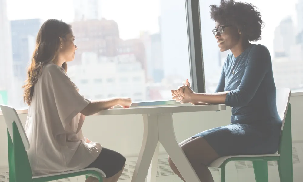 Two women sitting on the table talking.
